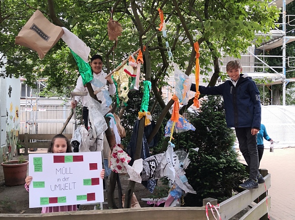 Kunstprojekt: Kinder, die einen Baum mit Plastikmüll geschmückt haben 