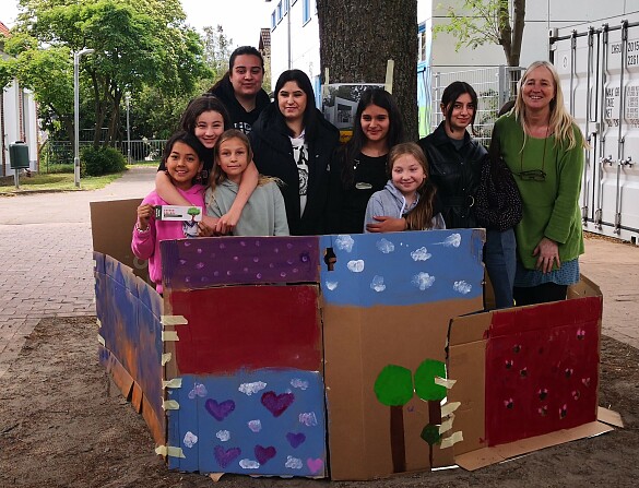 Kunstprojekt: Kinder, die mit Pappkartons eine Mauer um einen Baum erbaut haben