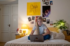 Jugendliche sitzt mit Laptop auf ihrem Bett