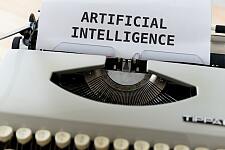 Schreibmaschine mit eingespanntem Papier, auf dem Artificial Intelligence (Englisch: künstliche Intelligenz) zu lesen ist.