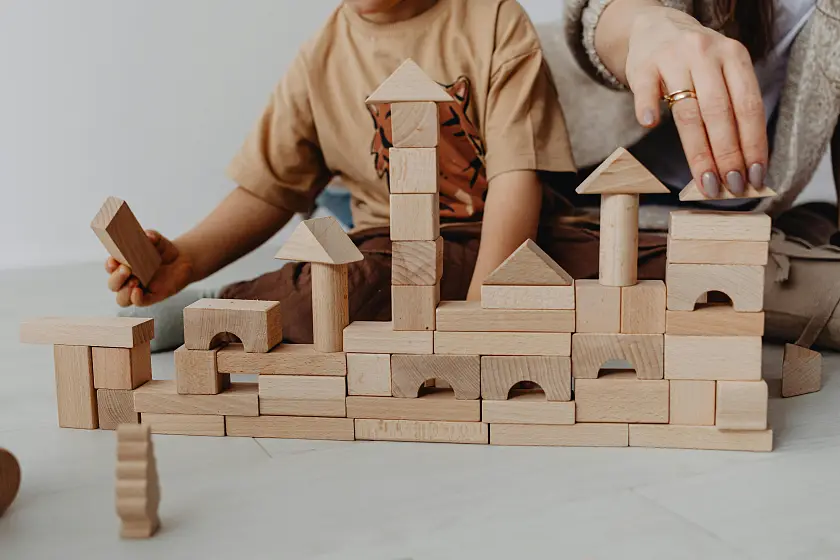 Ein Kind baut ein Haus aus Holzbauklötzen