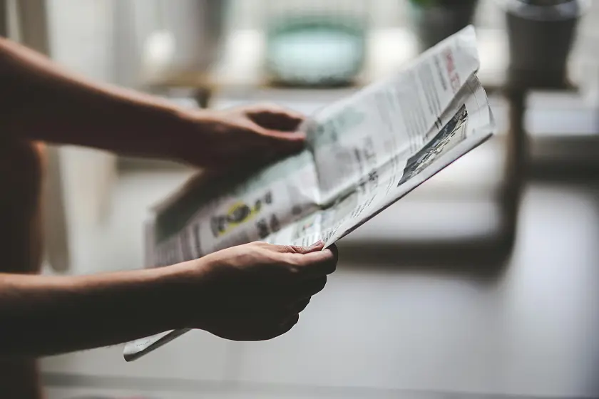 Eine Zeitung, die eine Person in den Händen hält