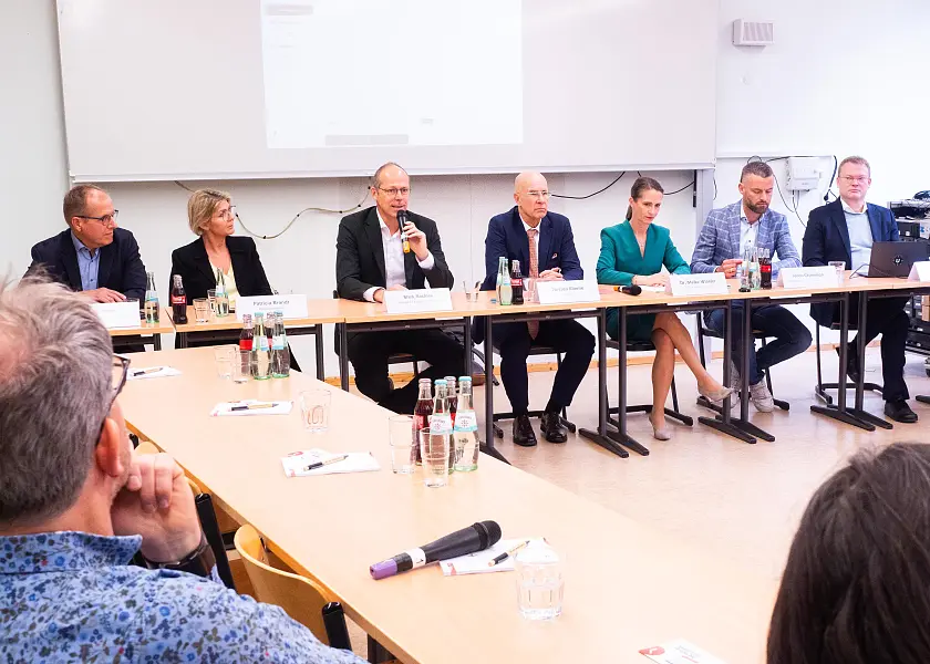Sieben Redner:innen an einem Tisch in einer Reihe sitzend - bei der PK Arbeitszeiterfassung 