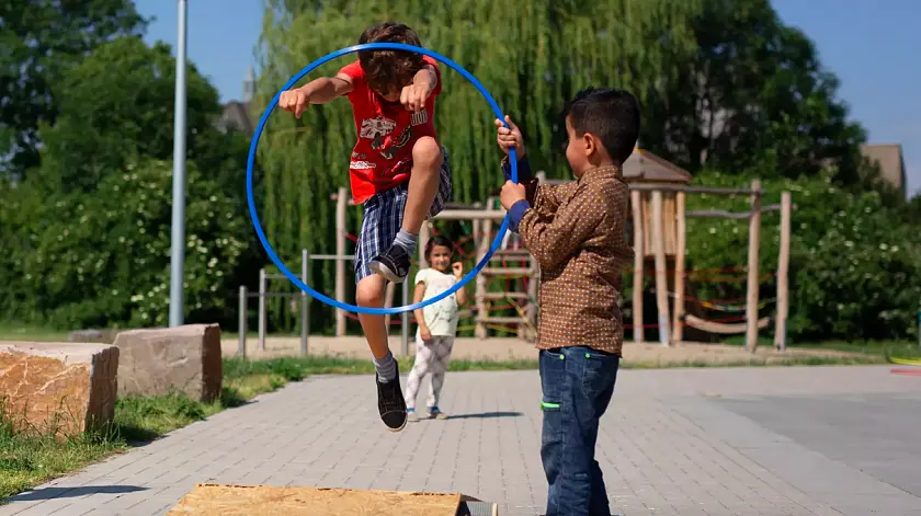 Kind, welches durch einen Reifen springt