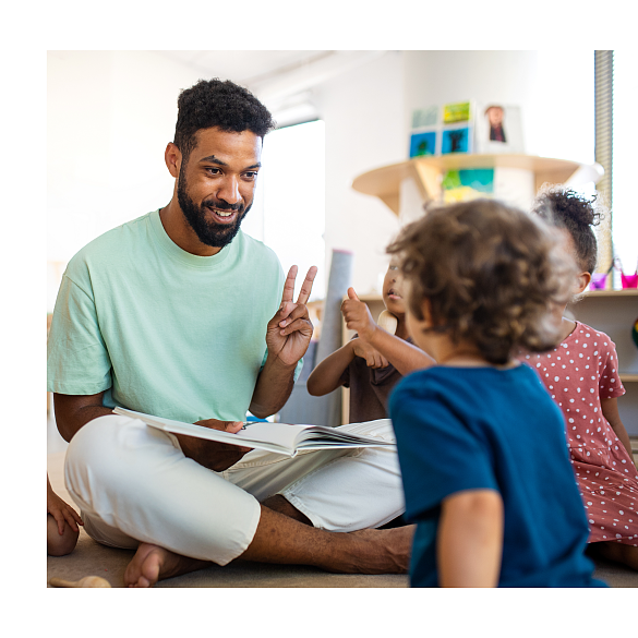Mann, die mit Kindern auf dem Boden sitzt und spielt