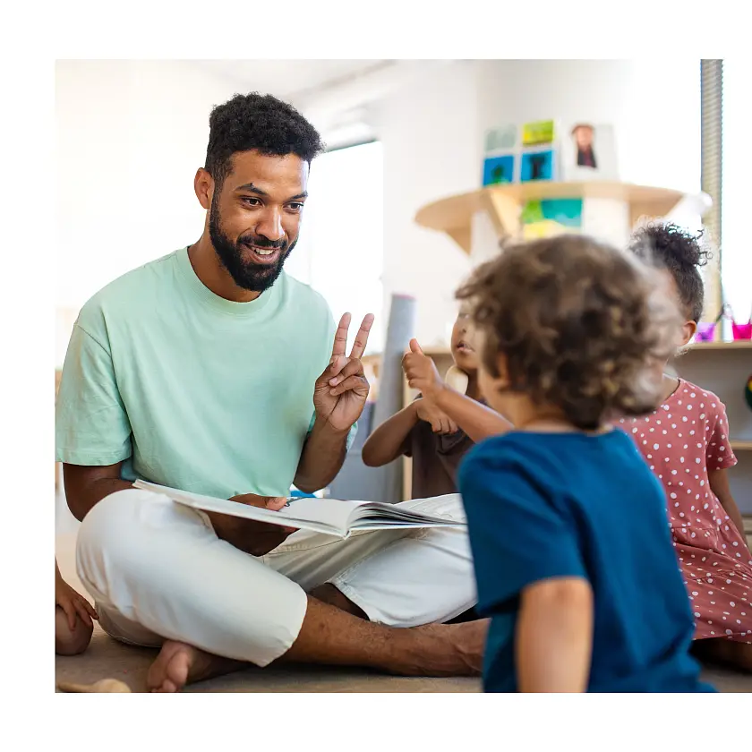 Mann, die mit Kindern auf dem Boden sitzt und spielt