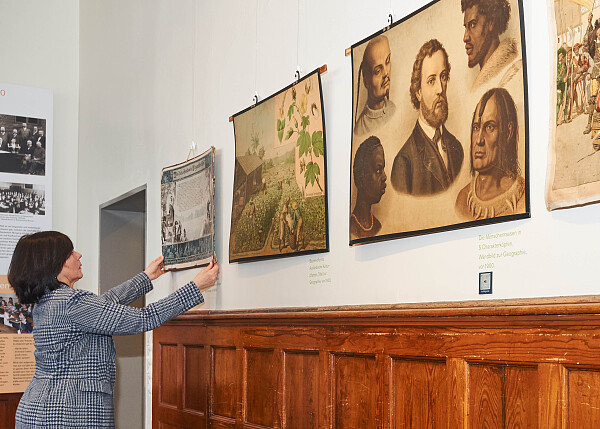 Frau im Schulmuseum, die alte Bilder aufhängt