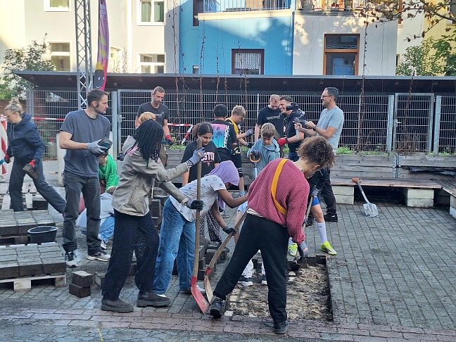 Schüler:innen auf ihrem Schulhof, die Pflastersteine entfernen