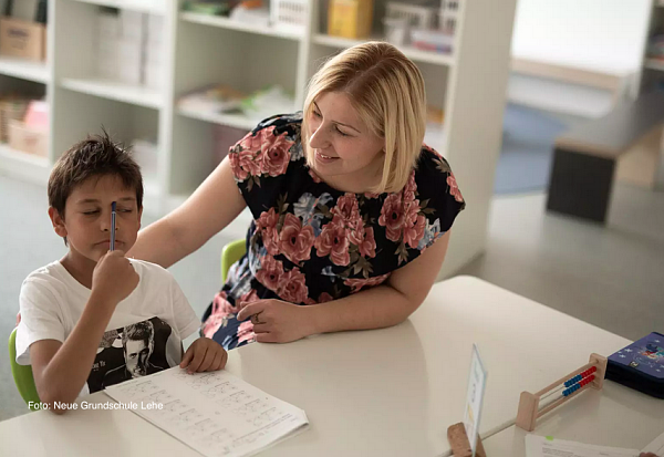 Lehrerin mit Schüler an einem Tisch. Foto: Neue Grundschule Bremerhaven