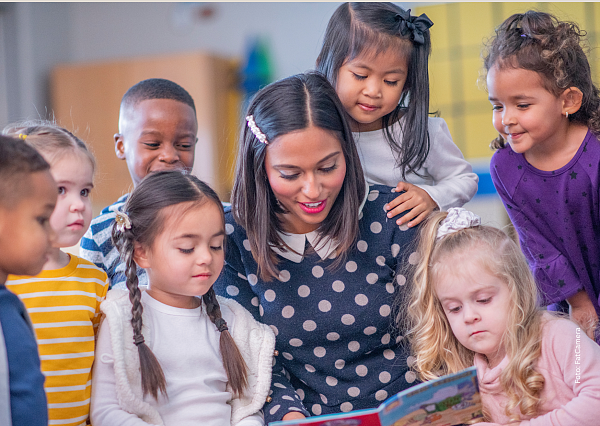 Frau, die von Kindern umgeben ist und die in ein Buch schauen