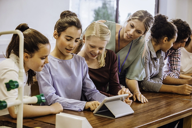 Lehrerin, die mit ihren Schülern etwas am Tablet macht
