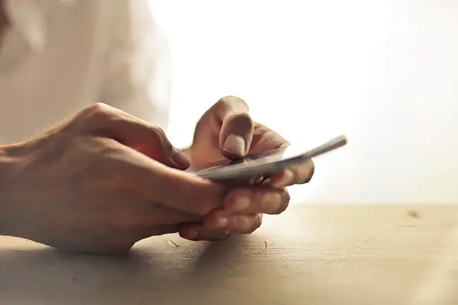 Auf dem Foto sind nur Hände zu sehen, die ein Smartphone in der Hand halten