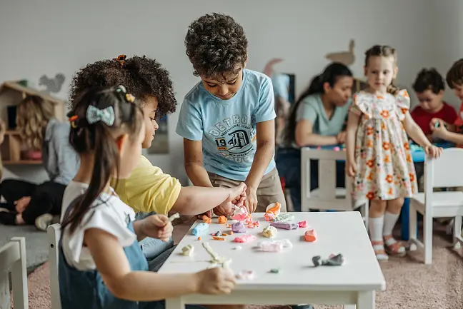 Kinder, die um einen Tisch stehen und basteln