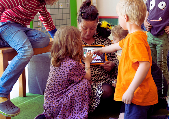 Drei Kinder sitzen mit einem Smartphone und Tablet auf dem Sofa 