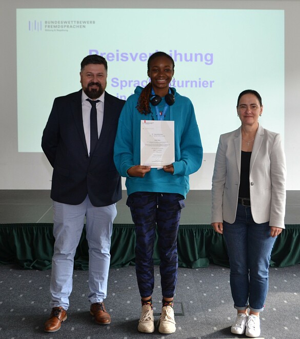 Foto: v.l.n.r.:  Michael Remmy (Leiter des Bundeswettbewerb Fremdsprachen), Preisträgerin Leslie Maya, Michaela Barthel (Vorsitzende der Bundesjury des Bundeswettbewerb Fremdsprachen SOLO)