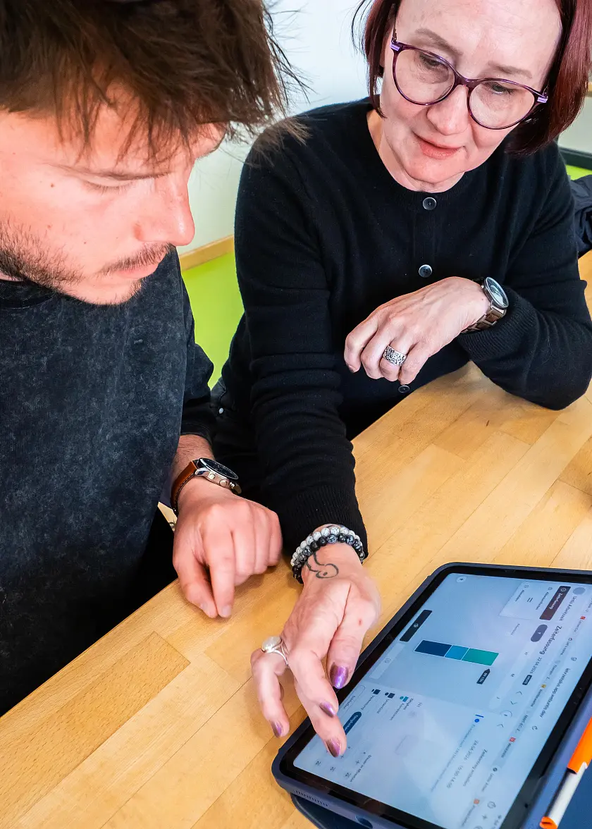 Zwei Lehkräfte, die ihre Arbeitszeit in die Arbeitszeiterfassungs-App eintragen 