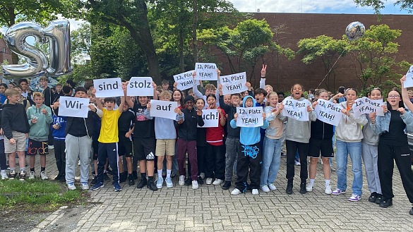 Schüler:innen stehen mit Schildern 