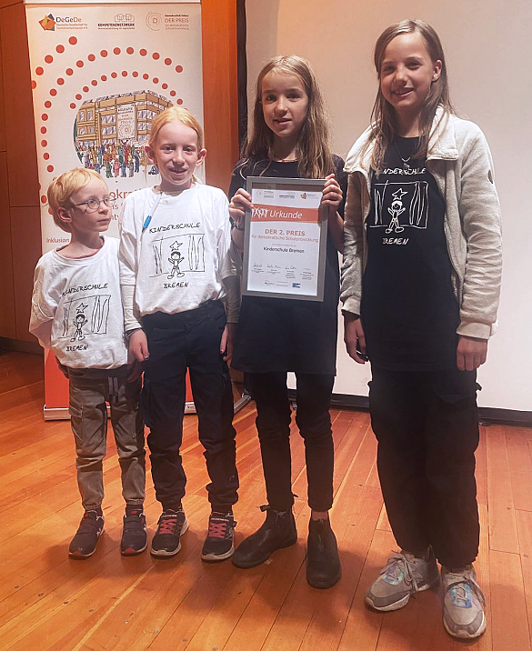 Kinder von der Kinderschule, die den 2. Preis für demokratische Schulentwicklung in der Hand halten