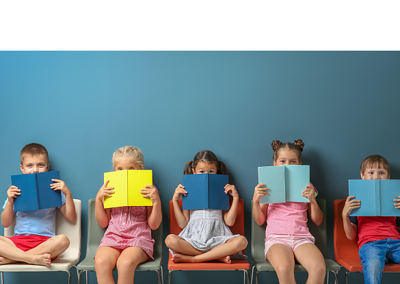 Fünf Kinder, die in einer Reihe sitzen und sich Bücher vor das Gesicht halten