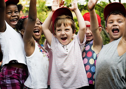 Kinder, die sich freuen und die Hände in die Luft heben