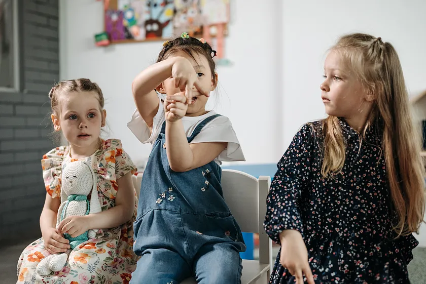 Zwei Erzieher:innen, die in einer Kita eine Aktion starten mit Kindergartenkindern